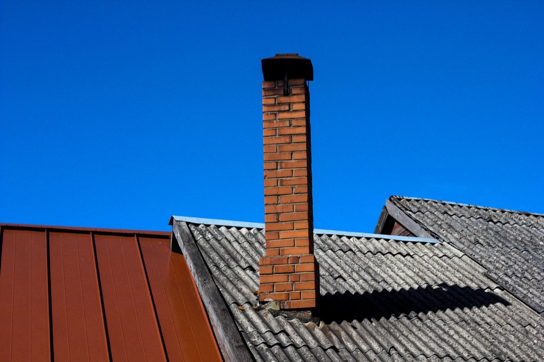 Cheminée en briques sur un toit de tuiles, ciel bleu