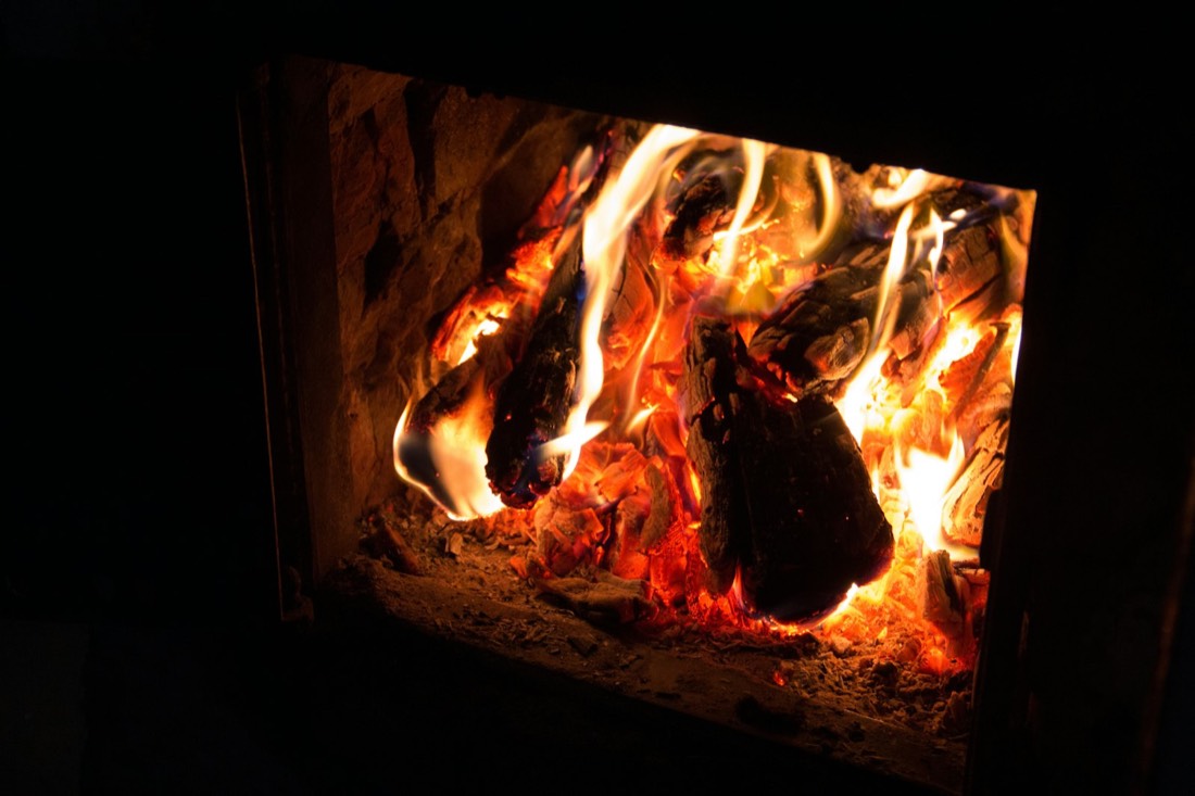 Feu de bûches vu à travers la vitre d'un poêle, gros plan